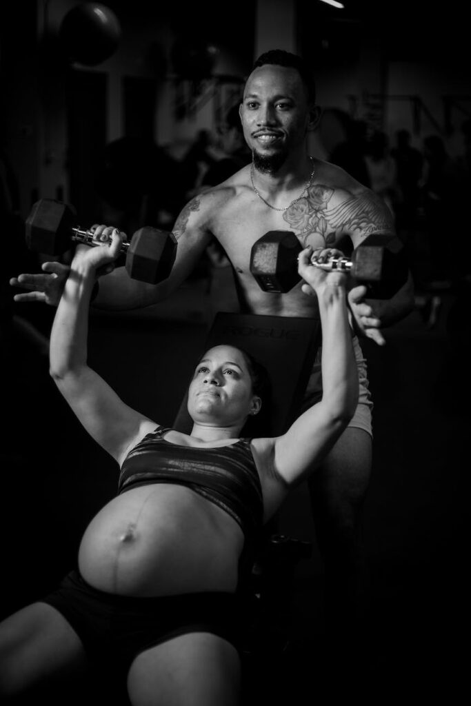 a woman in black tank top and shorts holding a dumbbell